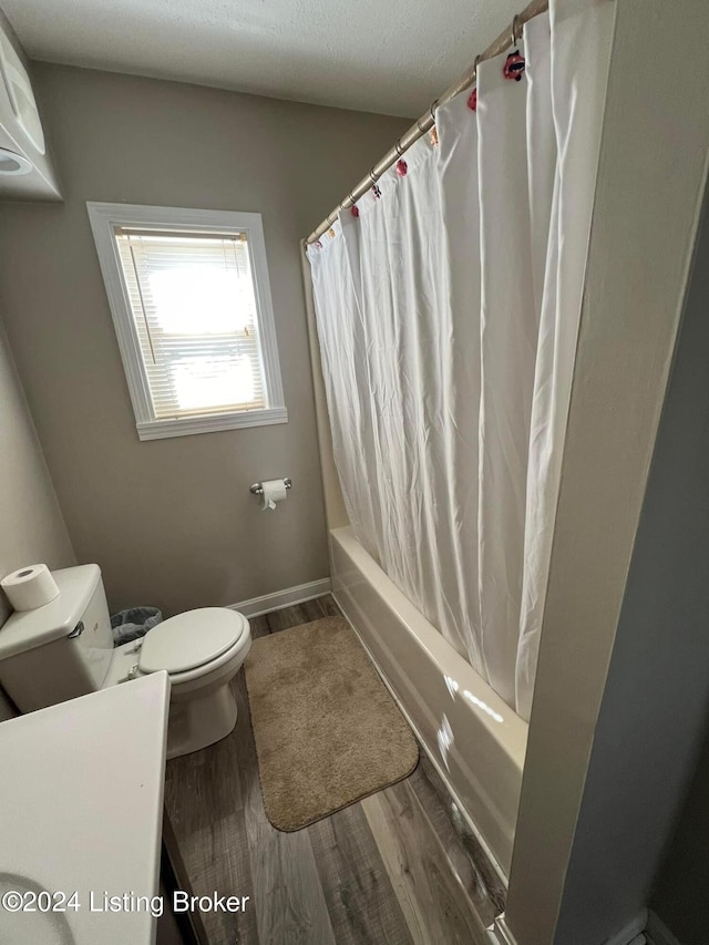 bathroom featuring hardwood / wood-style floors, toilet, a textured ceiling, and shower / tub combo with curtain