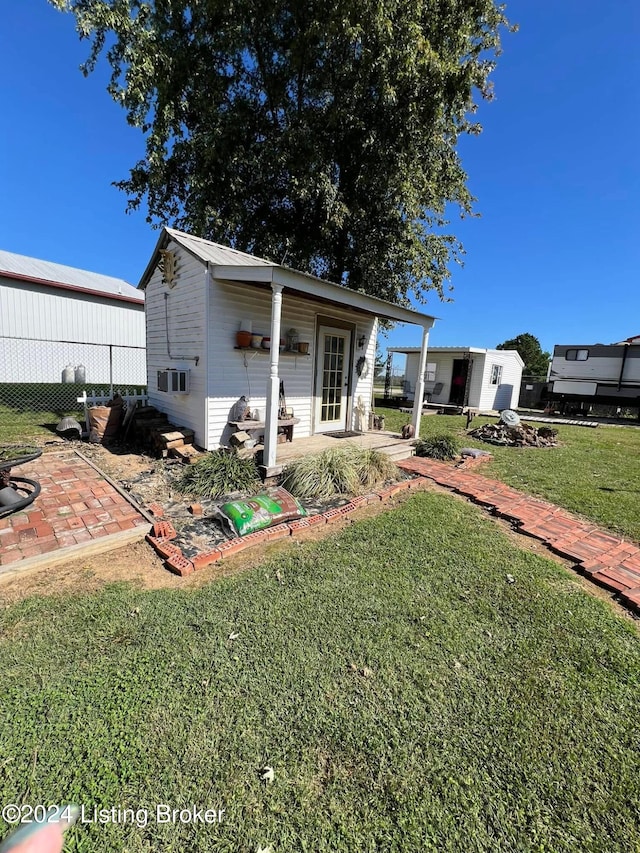 back of property with an outdoor structure, a patio area, and a yard