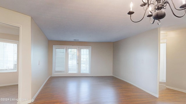 spare room featuring a notable chandelier and hardwood / wood-style floors