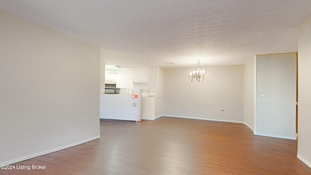 unfurnished room featuring dark wood-type flooring, an inviting chandelier, and a textured ceiling