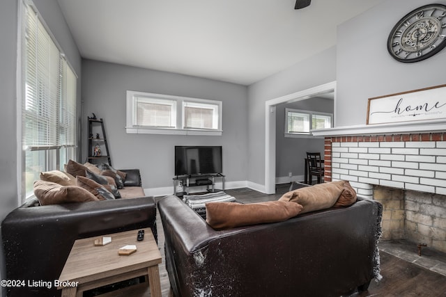 living room with a brick fireplace and dark hardwood / wood-style flooring