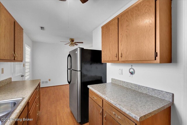 kitchen with ceiling fan, light hardwood / wood-style flooring, stainless steel fridge, and sink