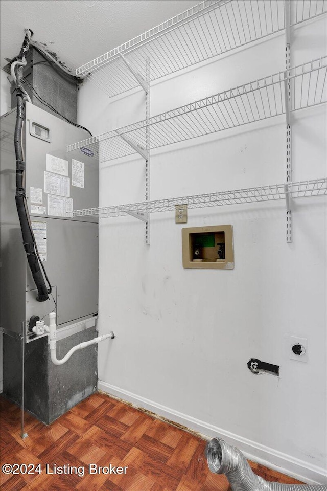 laundry area with dark parquet flooring, heating unit, hookup for a washing machine, and electric dryer hookup