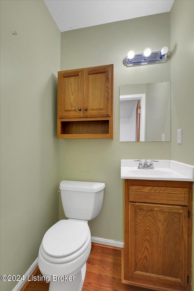 bathroom with a textured ceiling, hardwood / wood-style floors, vanity, and toilet