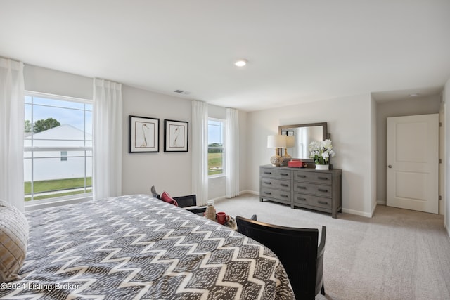 bedroom with light colored carpet and multiple windows