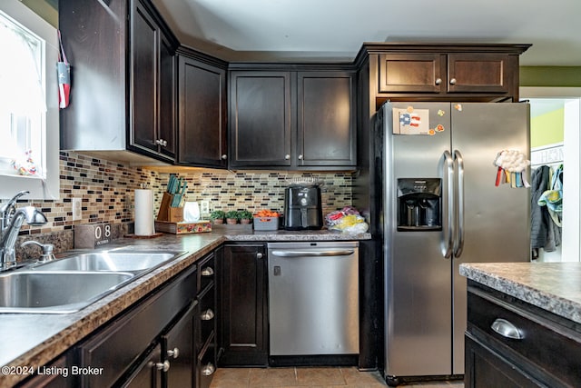 kitchen with appliances with stainless steel finishes, sink, light tile patterned floors, and dark brown cabinets