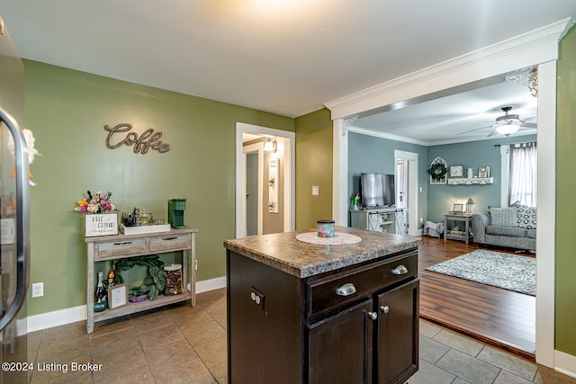 kitchen featuring light wood-type flooring, dark brown cabinetry, ceiling fan, a center island, and ornamental molding