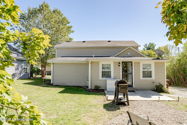 rear view of house featuring a lawn and a patio