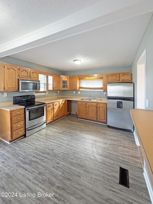 kitchen with a textured ceiling, stainless steel appliances, sink, and light hardwood / wood-style flooring