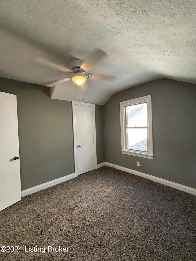 carpeted spare room featuring lofted ceiling, ceiling fan, and a textured ceiling