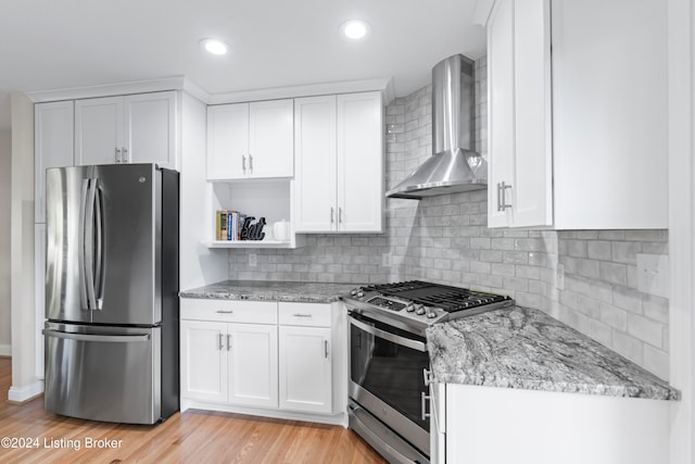 kitchen with white cabinetry, stainless steel appliances, and wall chimney range hood