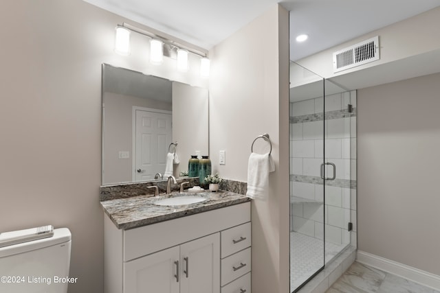 bathroom featuring vanity, a shower with shower door, and toilet