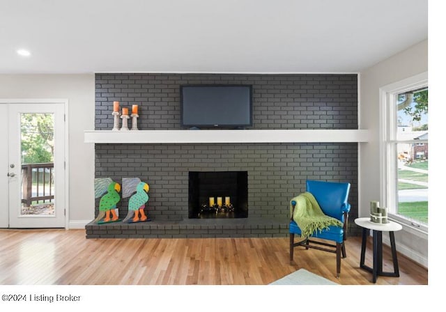 living room with a healthy amount of sunlight, wood-type flooring, and a brick fireplace