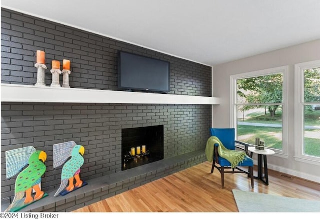 interior space featuring hardwood / wood-style flooring, a fireplace, and brick wall