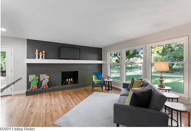 living room with hardwood / wood-style flooring, a wealth of natural light, and a brick fireplace