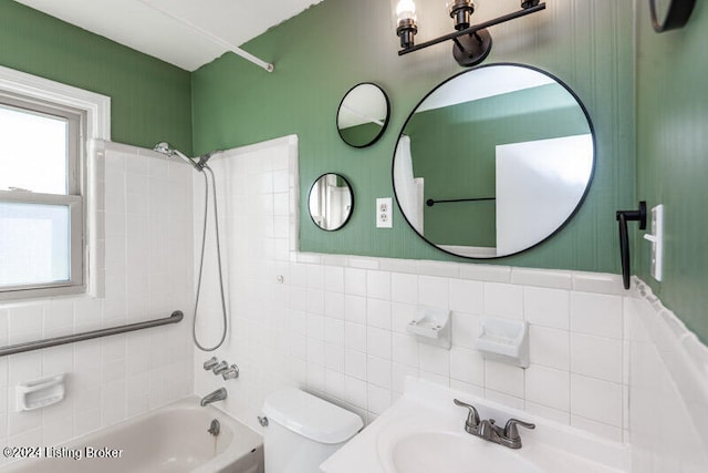 full bathroom with tile walls, tiled shower / bath, sink, and toilet