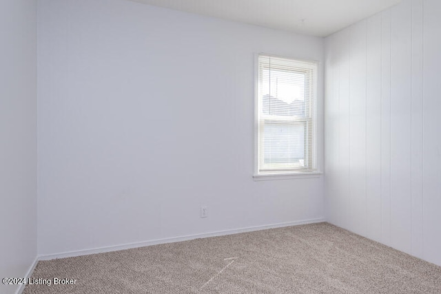 carpeted empty room featuring wooden walls