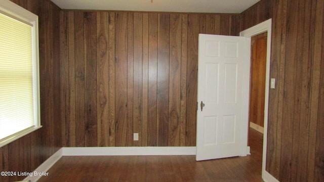 unfurnished room with wood walls and dark hardwood / wood-style flooring