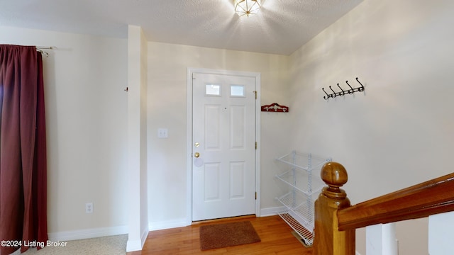 foyer entrance with light wood-type flooring and a textured ceiling