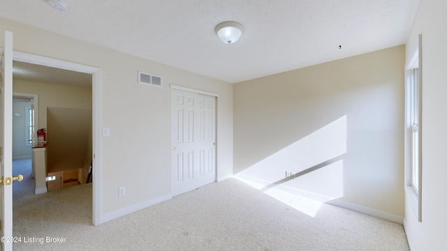 unfurnished bedroom featuring a closet and light colored carpet