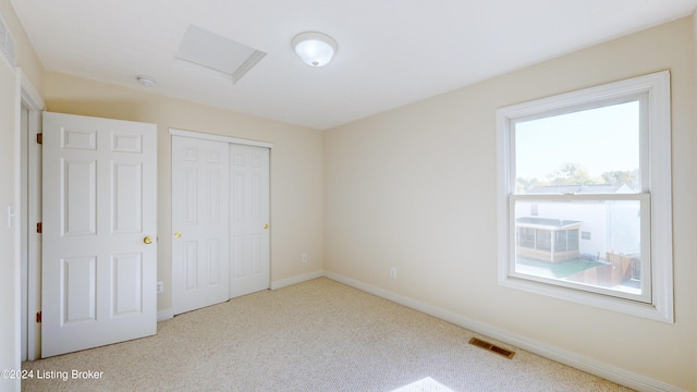 unfurnished bedroom with a closet, multiple windows, and light carpet