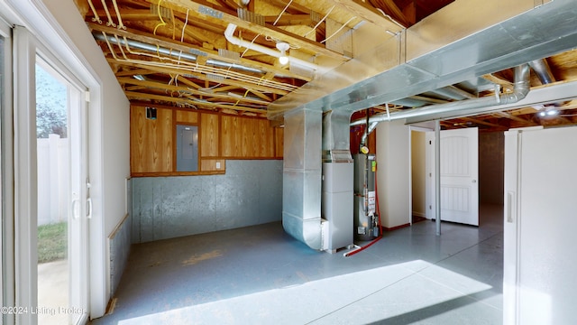 basement featuring gas water heater, electric panel, heating unit, and a healthy amount of sunlight