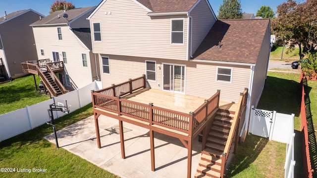 rear view of property featuring a deck, a lawn, and a patio area