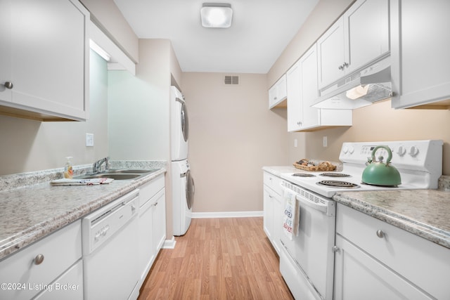 kitchen with sink, white appliances, stacked washer / dryer, white cabinetry, and light wood-type flooring