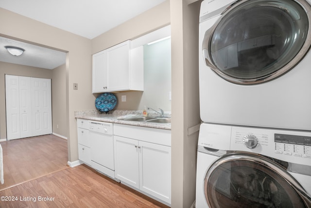 laundry room featuring light wood-type flooring, stacked washer / drying machine, and sink