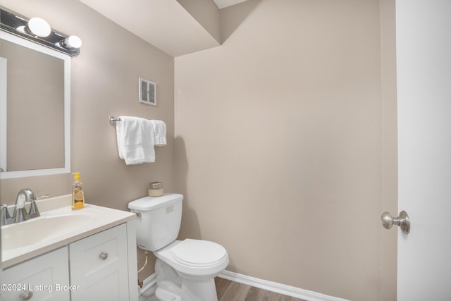 bathroom with wood-type flooring, vanity, and toilet