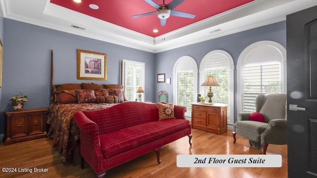 bedroom featuring a raised ceiling, ornamental molding, hardwood / wood-style flooring, and ceiling fan