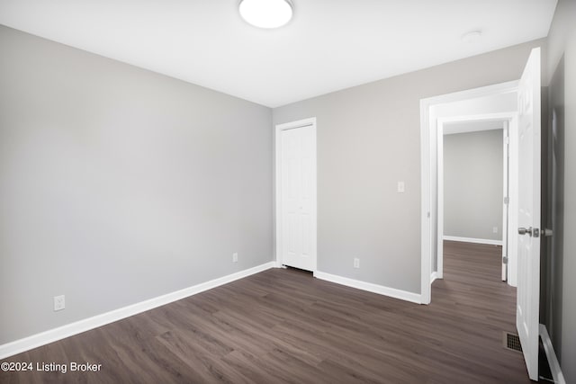 unfurnished bedroom featuring dark wood-type flooring and a closet