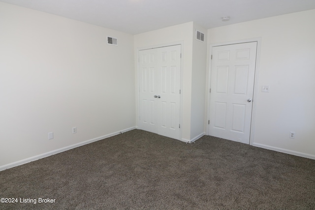 unfurnished bedroom with a closet and dark colored carpet