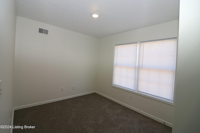 unfurnished room with dark carpet and plenty of natural light