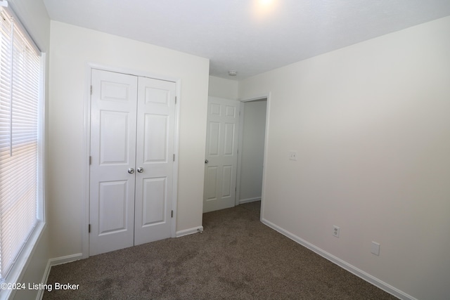 unfurnished bedroom with a closet and dark carpet