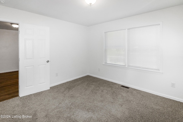 unfurnished room featuring dark colored carpet