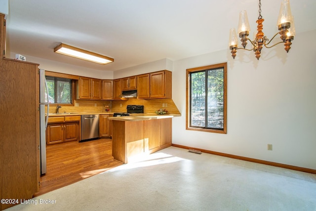 kitchen with decorative light fixtures, plenty of natural light, stainless steel appliances, and tasteful backsplash