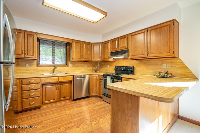 kitchen with stainless steel appliances, kitchen peninsula, tasteful backsplash, and sink