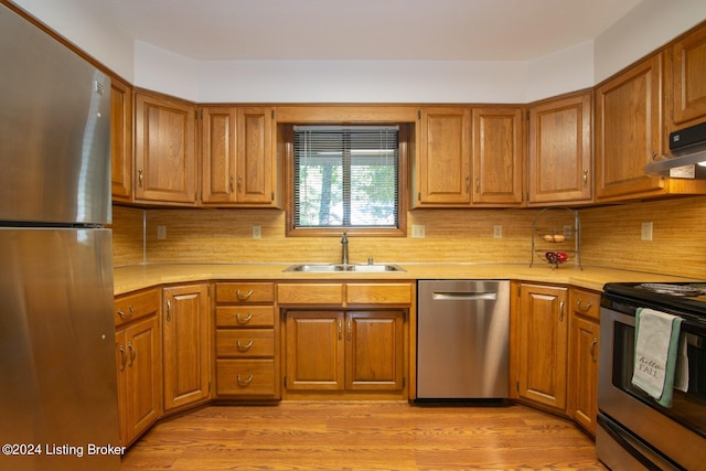 kitchen featuring backsplash, appliances with stainless steel finishes, sink, and light wood-type flooring