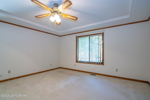 unfurnished room with carpet floors, a tray ceiling, crown molding, and ceiling fan