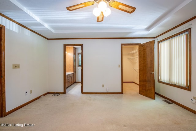 unfurnished bedroom with ceiling fan, a closet, light carpet, a walk in closet, and ensuite bathroom