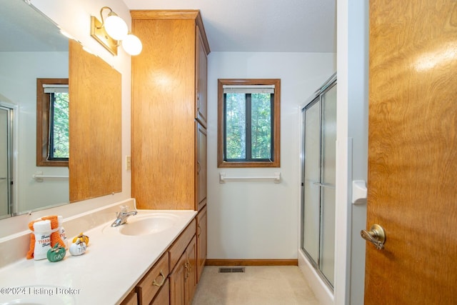 bathroom featuring vanity, a shower with door, and a healthy amount of sunlight