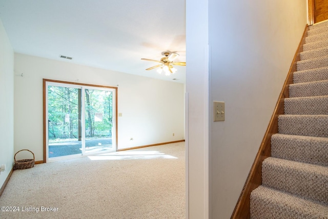 stairs featuring ceiling fan and carpet floors