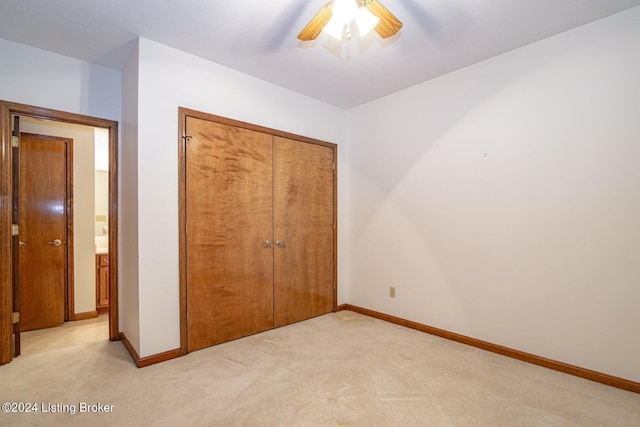 unfurnished bedroom featuring ceiling fan, a closet, and light carpet