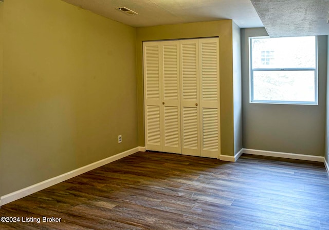 unfurnished bedroom with dark hardwood / wood-style flooring and a closet