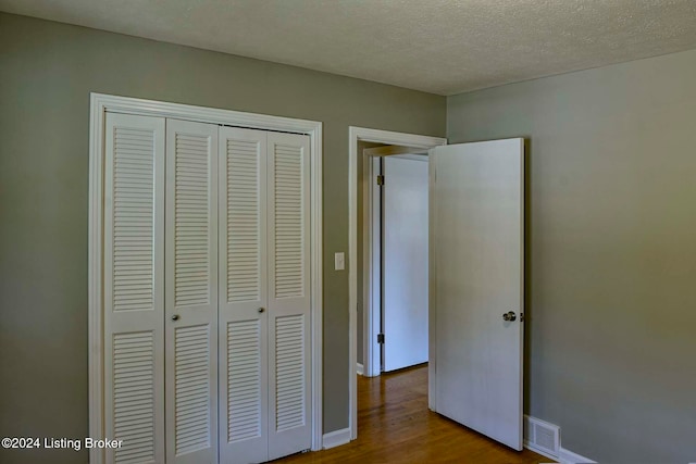 unfurnished bedroom with light hardwood / wood-style floors, a closet, and a textured ceiling