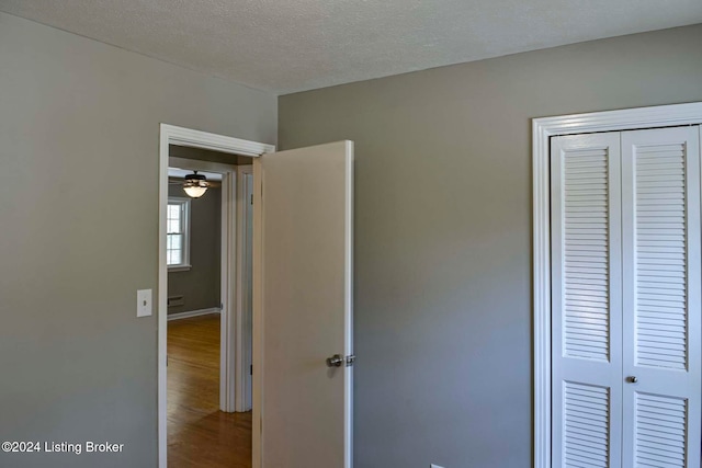 unfurnished bedroom featuring hardwood / wood-style flooring, a closet, and a textured ceiling