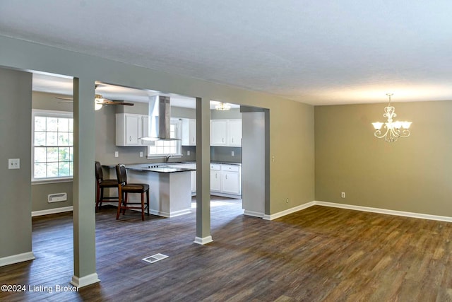 unfurnished living room featuring dark hardwood / wood-style floors and ceiling fan with notable chandelier