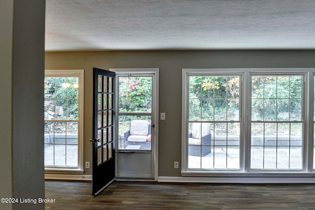 doorway with dark hardwood / wood-style floors and a textured ceiling