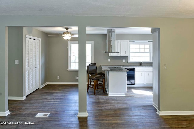 kitchen with a kitchen bar, sink, black dishwasher, wall chimney range hood, and white cabinets